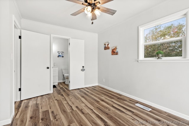 unfurnished bedroom with connected bathroom, ceiling fan, hardwood / wood-style floors, and crown molding