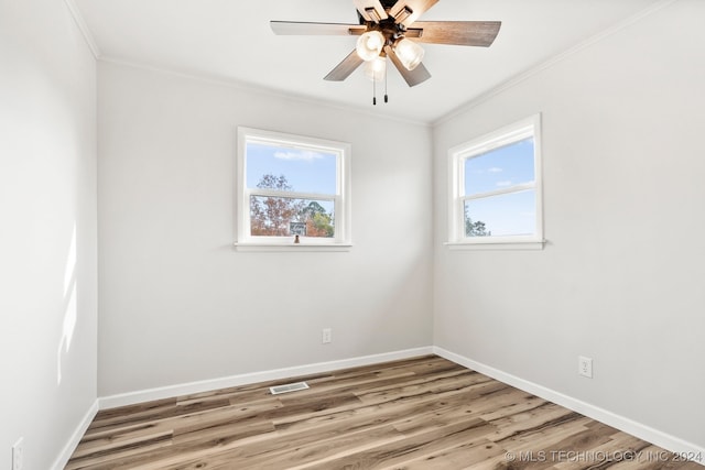 empty room featuring a wealth of natural light, light hardwood / wood-style floors, and ornamental molding