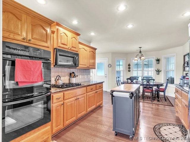 kitchen featuring a center island, black appliances, decorative light fixtures, light hardwood / wood-style floors, and a chandelier