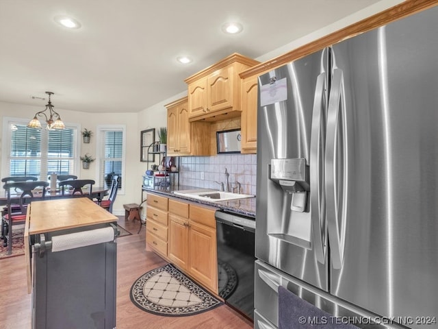 kitchen with pendant lighting, dark wood-type flooring, sink, stainless steel fridge, and black dishwasher