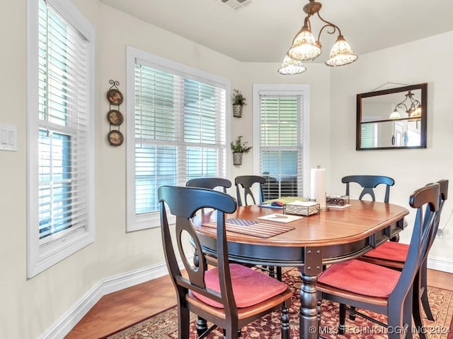 dining space featuring hardwood / wood-style flooring, an inviting chandelier, and a wealth of natural light