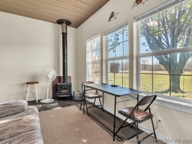 sunroom featuring a wood stove and wooden ceiling