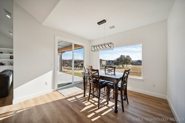 dining room with wood-type flooring and vaulted ceiling