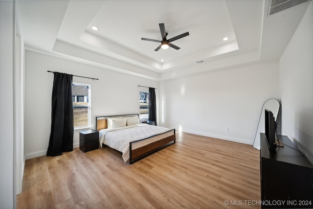 bedroom with a tray ceiling, light hardwood / wood-style flooring, and ceiling fan