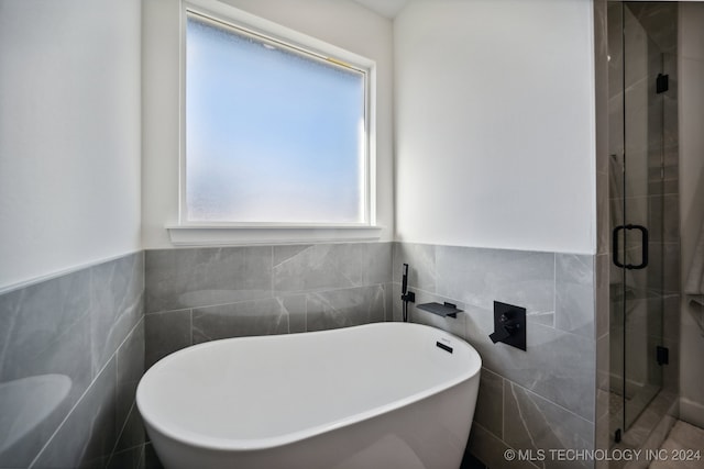 bathroom featuring independent shower and bath and tile walls