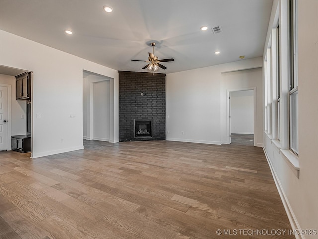 unfurnished living room with a fireplace, ceiling fan, and light hardwood / wood-style floors