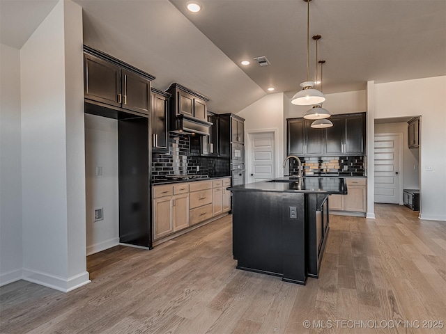 kitchen featuring wood-type flooring, sink, a center island with sink, and backsplash