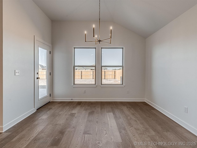 unfurnished dining area with hardwood / wood-style flooring, lofted ceiling, and a notable chandelier