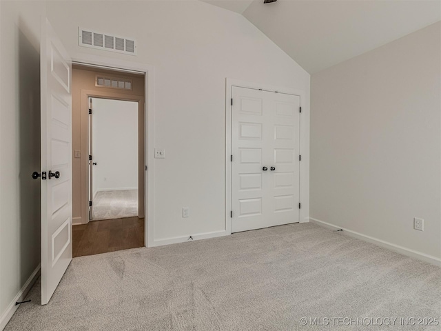 unfurnished bedroom with carpet floors, vaulted ceiling, and a closet