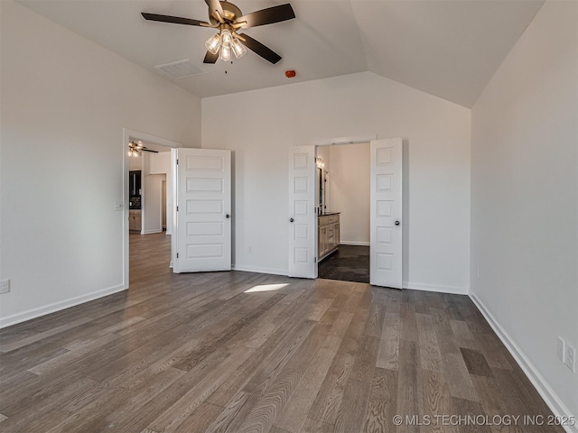 unfurnished bedroom featuring lofted ceiling, ensuite bath, dark hardwood / wood-style floors, and ceiling fan