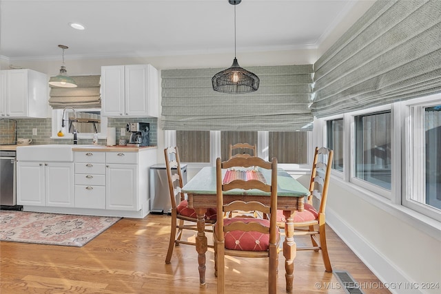 dining space with light wood-type flooring, ornamental molding, and sink