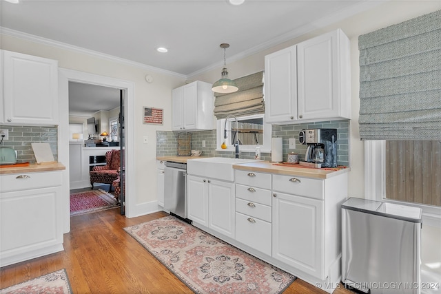 kitchen featuring white cabinetry, sink, light hardwood / wood-style flooring, stainless steel dishwasher, and pendant lighting