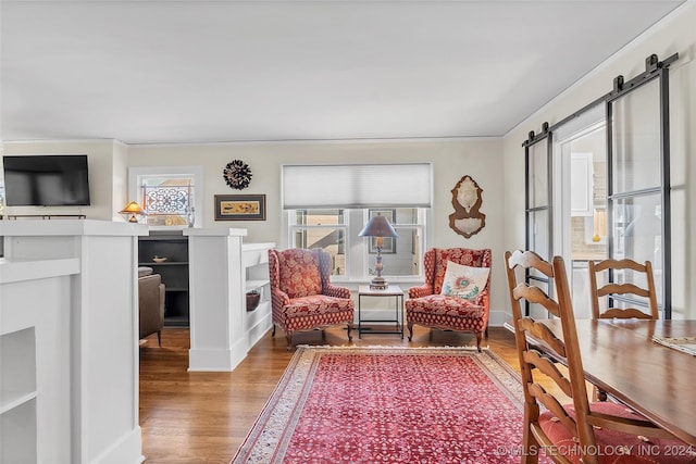 sitting room with wood-type flooring, a barn door, and ornamental molding