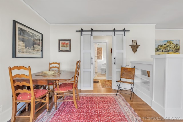 dining space with hardwood / wood-style floors, a barn door, and ornamental molding