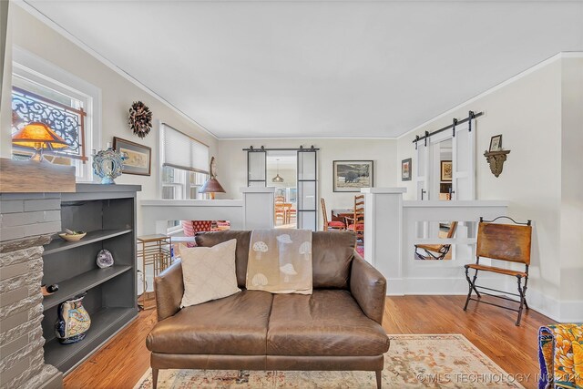 living room featuring a barn door, light wood-type flooring, and crown molding