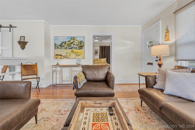 living room featuring a barn door, ornamental molding, and light wood-type flooring