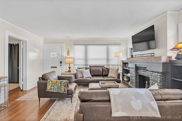 living room featuring hardwood / wood-style flooring, a fireplace, and crown molding