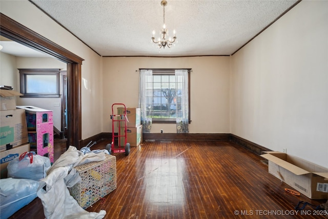 interior space featuring hardwood / wood-style floors, a notable chandelier, baseboards, and a textured ceiling