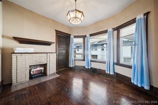 unfurnished living room featuring a fireplace, dark wood-type flooring, and an inviting chandelier