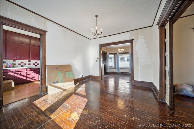 spare room featuring baseboards, a chandelier, crown molding, and hardwood / wood-style flooring