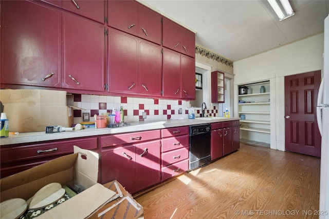 kitchen with a sink, black dishwasher, light wood finished floors, and red cabinets