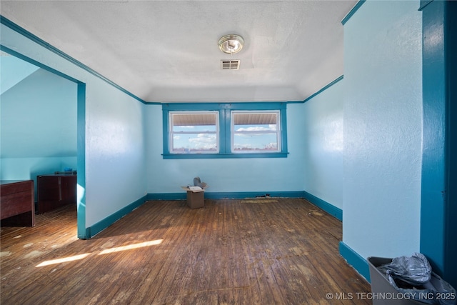 spare room featuring visible vents, baseboards, a textured ceiling, and hardwood / wood-style flooring