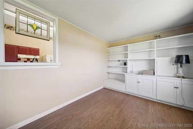 interior space with baseboards, wood finished floors, and vaulted ceiling