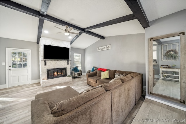 living room with ceiling fan, lofted ceiling with beams, light wood-type flooring, and a fireplace