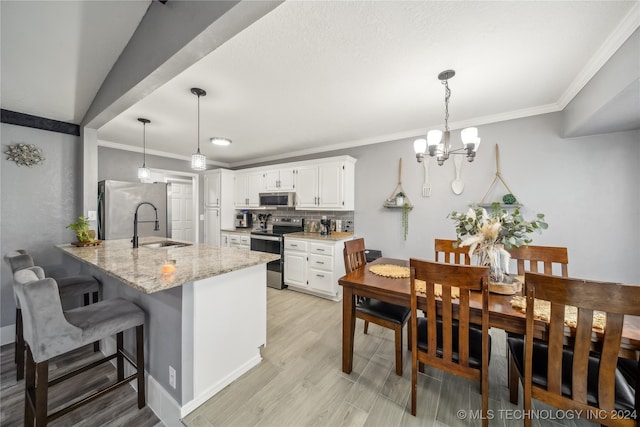 kitchen with white cabinetry, sink, stainless steel appliances, kitchen peninsula, and decorative light fixtures