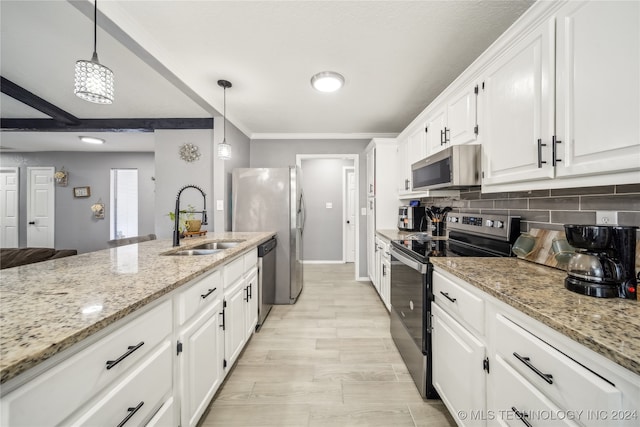 kitchen featuring light stone countertops, appliances with stainless steel finishes, sink, pendant lighting, and white cabinetry