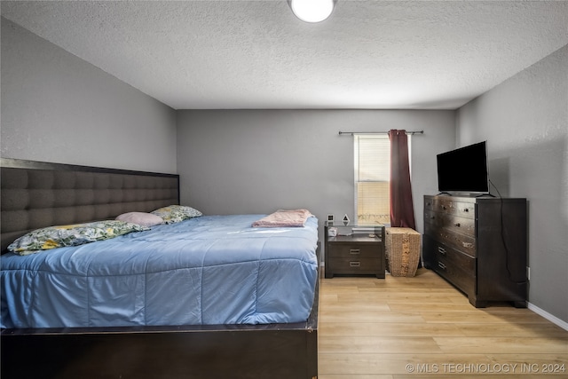 bedroom with a textured ceiling and light hardwood / wood-style flooring