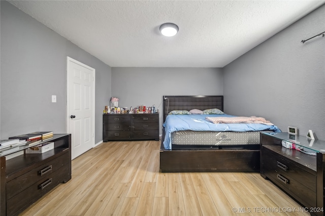 bedroom featuring light hardwood / wood-style flooring and a textured ceiling