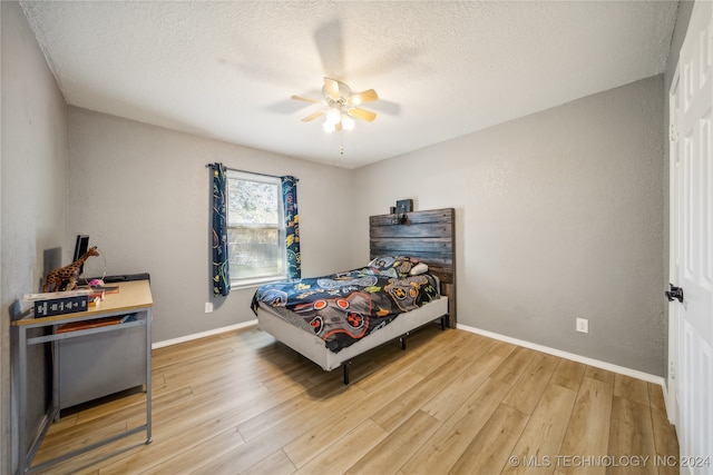 bedroom with ceiling fan, a textured ceiling, and hardwood / wood-style flooring