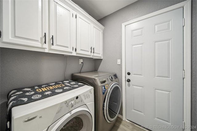 washroom with washing machine and clothes dryer, light hardwood / wood-style flooring, and cabinets