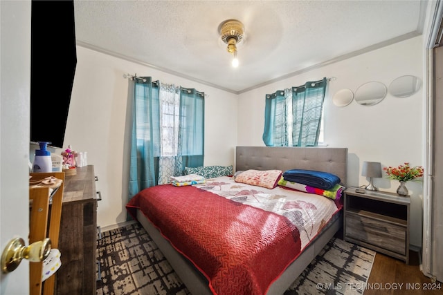 bedroom featuring hardwood / wood-style floors, ceiling fan, ornamental molding, and a textured ceiling