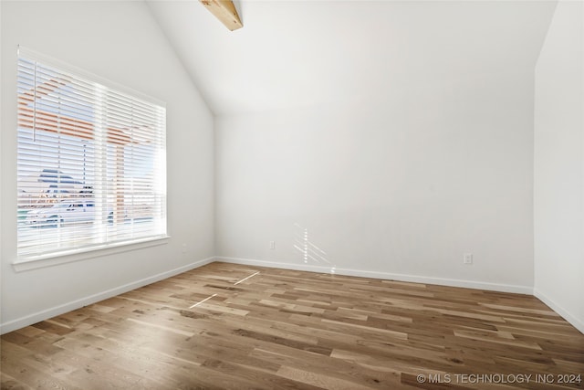 empty room featuring hardwood / wood-style flooring and vaulted ceiling