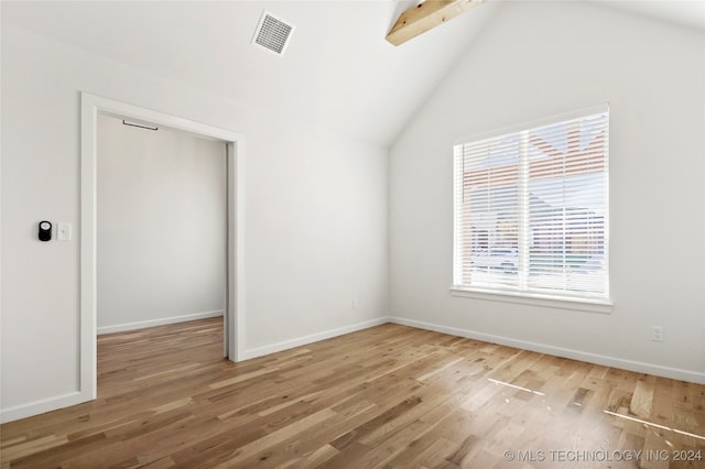 unfurnished room featuring lofted ceiling with beams and hardwood / wood-style flooring