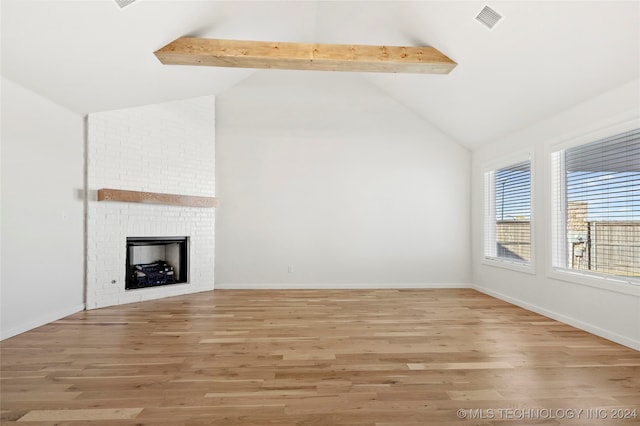 unfurnished living room featuring beam ceiling, a fireplace, light hardwood / wood-style flooring, and high vaulted ceiling