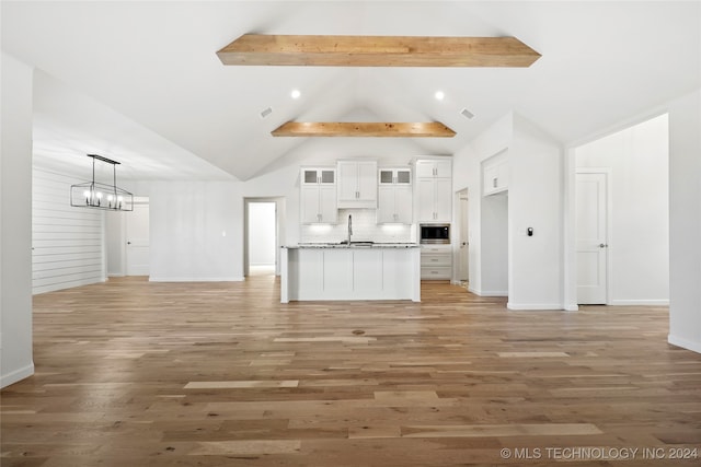 kitchen featuring light stone countertops, decorative light fixtures, white cabinets, hardwood / wood-style floors, and stainless steel microwave