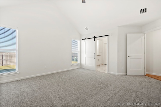 unfurnished bedroom featuring light carpet, a barn door, and multiple windows