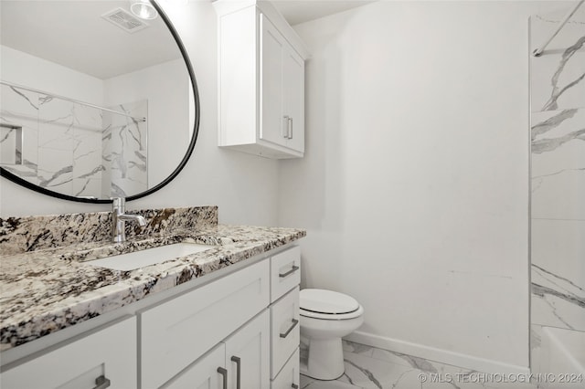 bathroom with a tile shower, vanity, and toilet