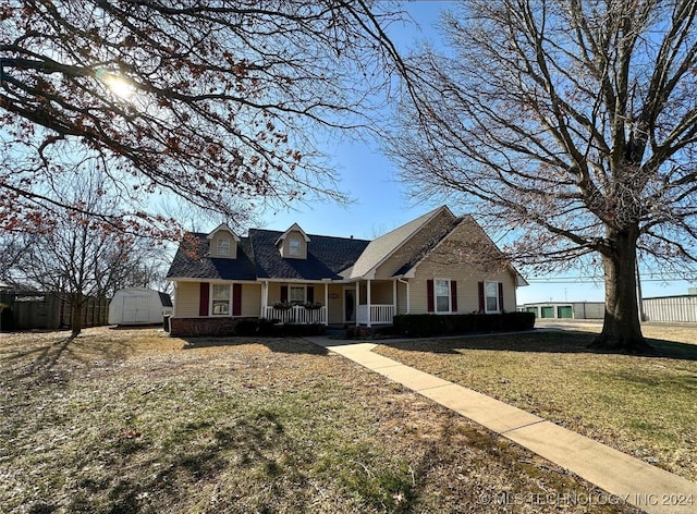 view of front of property featuring covered porch, a shed, and a front lawn