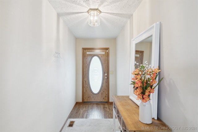 doorway to outside featuring wood-type flooring and a textured ceiling