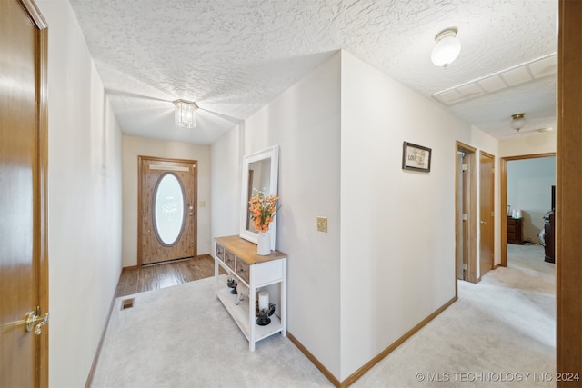 entryway with light colored carpet and a textured ceiling