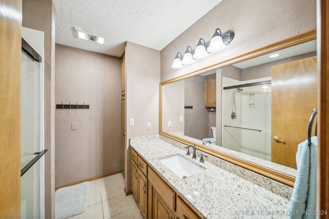 bathroom featuring an enclosed shower, a textured ceiling, vanity, tile patterned flooring, and toilet