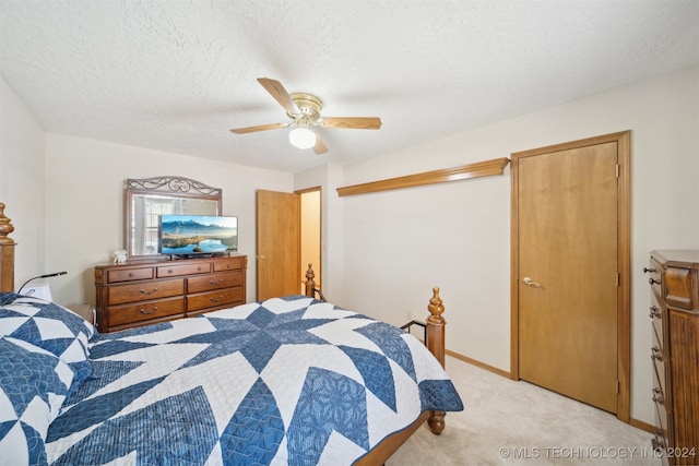 bedroom featuring a textured ceiling, light colored carpet, and ceiling fan