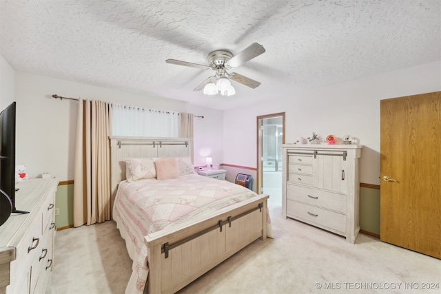 bedroom with ensuite bath, ceiling fan, light colored carpet, and a textured ceiling