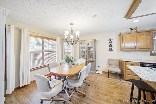 dining space with a chandelier, a textured ceiling, and light wood-type flooring