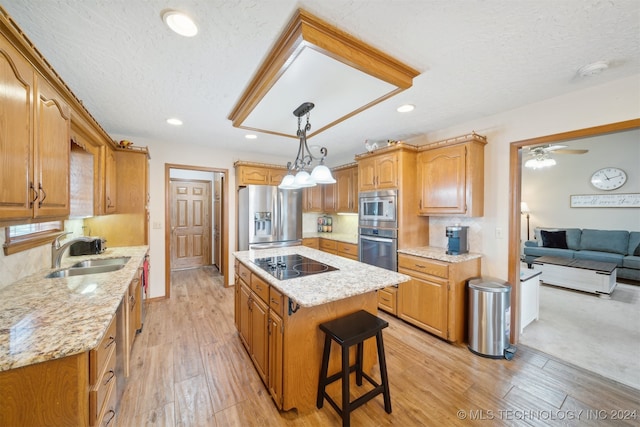 kitchen with sink, light hardwood / wood-style flooring, a textured ceiling, a kitchen island, and appliances with stainless steel finishes