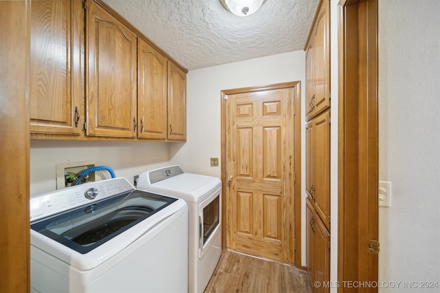 washroom featuring cabinets, washing machine and dryer, a textured ceiling, and light hardwood / wood-style flooring